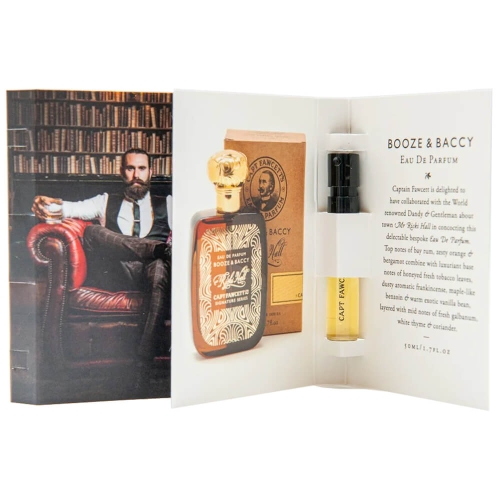 Eau De Parfum Booze & Baccy w ciemnej butelce z złotą zakrętką i wzorem na etykiecie; obok próbkowy flakonik, na tle ilustracji przedstawiającej mężczyznę w eleganckim garniturze siedzącego na skórzanej sofie z książkami w tle.