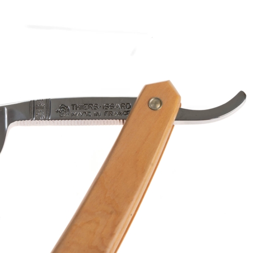 Brzytwa do golenia Thiers Issard z metalowym ostrzem i drewnianą rączką w kolorze jasnego drewna, widok z boku. Na ostrzu wygrawerowane napisy THIERS-ISARD MADE IN FRANCE. Prosty, biały background.