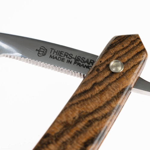 Brzytwa do golenia Thiers Issard z rączką bocote, widok z boku; stalowe ostrze z wygrawerowanym napisem THIERS-ISSARD MADE IN FRANCE, rączka z charakterystycznym, ciemnym wzorem drewna, metalowy guzik mocujący.