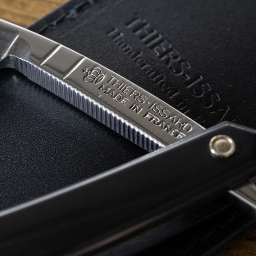 Brzytwa Thiers Issard Special Coiffeur Black 6/8 na czarnym tle, z lśniącym stalowym ostrzem i matową czarną rękojeścią z grawerem THIERS-ISSARD MADE IN FRANCE.