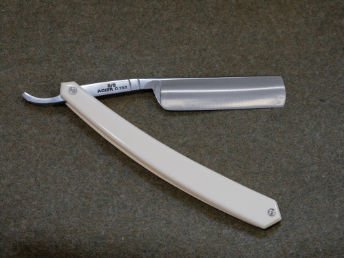 Brzytwa do golenia Thiers Issard Le Dandy White 5/8 w kolorze białym z gładką rączką i metalowym ostrzem. Produkt leży na jednolitym tle. Zbliżenie na fakturę ostrza i odwzorowanie napisów na nim.