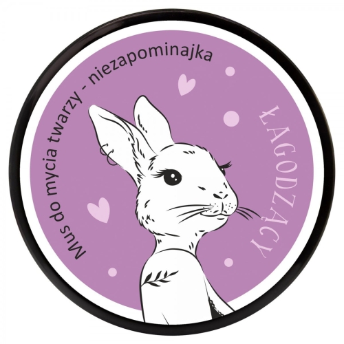 Mus do mycia twarzy Niezapominajka w opakowaniu 100 ml, okrągłe, z widocznym rysunkiem białego królika na fioletowym tle. Na etykiecie widoczne napisy: Mus do mycia twarzy - niezapominajka oraz Łagodzący. Opakowanie ma czarną ramkę.