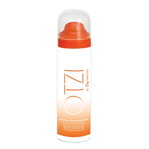 Spray antybakteryjny EasyPiercing 50 ml, białe cylindryczne opakowanie z pomarańczowym gradientem i napisem OTZI oraz informacją o działaniu antybakteryjnym. Zamknięty przezroczystą nakrętką, stoi na białym tle.