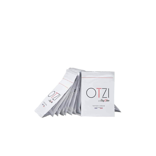 Krem do tatuażu w białej saszetce 4 ml z kolorowym logo OTZI i napisem TATTOO CREAM. Saszetki leżą w stosie, niektóre odwrócone, na jednolitym tle podkreślającym prostotę.