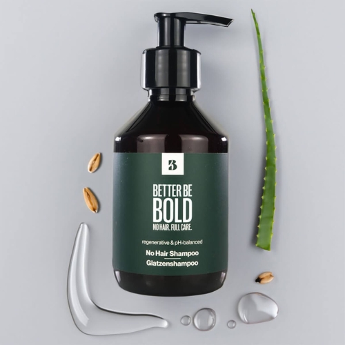 Czarna butelka 200 ml z pompką z regenerującym szamponem No Hair Shampoo i napisem Better Be Bold. Obok nasiona, kropla płynu i liść aloesu na jasnoszarym tle.
