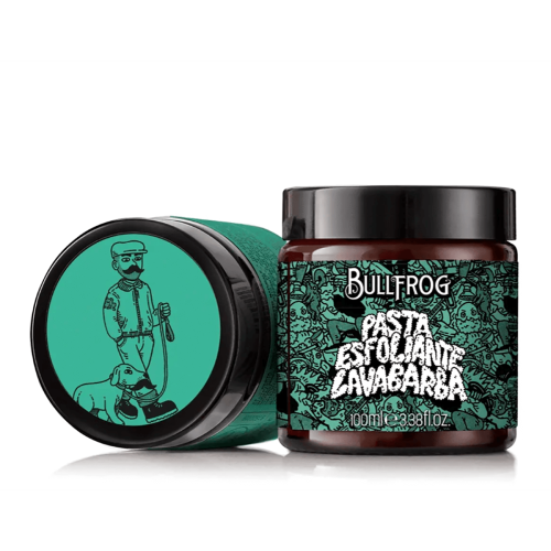 Bullfrog Peeling do brody 100 ml w ciemnym szklanym słoiku z zieloną etykietą z ilustracją mężczyzny z psem. Słoik ustawiony frontalnie na stole, obok zakrętka kontrastująca z etykietą. Napisy w języku hiszpańskim i pojemność widoczne.