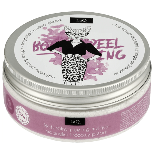 Naturalny peeling myjący w metalowym słoiku z etykietą LaQ, przedstawiającą kobietę w okularach i czarnej bluzce, z panterkową spódnicą. Na etykiecie różowe i białe napisy, zapach magnolii i różowego pieprzu. Słoik leży na płasko.