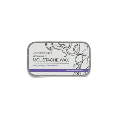 Wosk do wąsów Ylang Ylang i Sandalwood w prostokątnym, metalowym opakowaniu z białą etykietą MEDIUM HOLD MOUSTACHE WAX, nazwą zapachu, logo marki i delikatnym szarym wzorem.