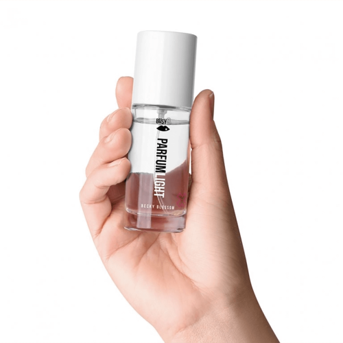 Woda toaletowa Becky Blossom 30 ml w przezroczystej butelce z białą zakrętką, trzymana w dłoni. Na butelce widoczne czarne napisy: „PARFUM LIGHT” oraz „BECKY BLOSSOM”. Interpretacja minimalistyczna, z prostym tłem, podkreślającym formę produktu.