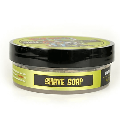 Mydło do golenia w okrągłym, przezroczystym opakowaniu z czarną pokrywką. Etykieta w kolorze zielonym z dużym napisem „SHAVE SOAP” na czarnym tle. Widoczny jest wzór graficzny na pokrywce. Produkt leży na białym tle.