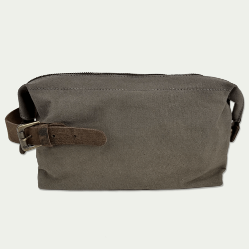 Kosmetyczka Birling Wash Bag w kolorze szarym z brązowym skórzanym paskiem, zamknięta na zamek błyskawiczny. Widok z boku, ukazujący prostokątny kształt i materiał zewnętrzny o gładkiej fakturze.