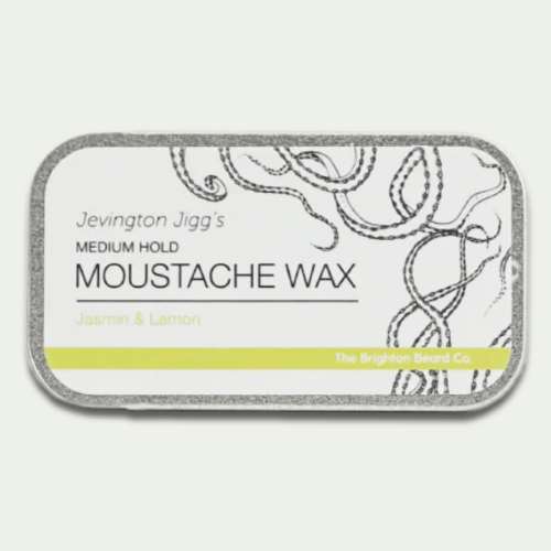 Wosk do wąsów w metalowej prostokątnej puszce z grafiką wąsów. Etykieta biała z szarymi i zielonymi akcentami, napisem MEDIUM HOLD MOUSTACHE WAX Jasmin & Lemon. Pojemność 15 g, puszka na jednolitym tle.