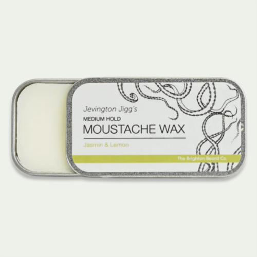 Wosk do wąsów w metalowym opakowaniu z grafiką w czarno-białej kolorystyce, z widocznymi napisami: Medium Hold Moustache Wax oraz Jasmin & Lemon. Opakowanie otwarte, ukazujące białą substancję. Niewielkie wymiary – idealny do podróży.
