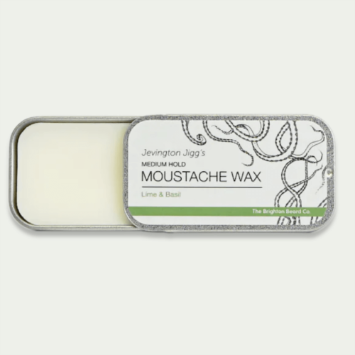 Wosk do wąsów w metalowej puszce o matowym wykończeniu, otwarta od góry. Widoczny napis MEDIUM HOLD MOUSTACHE WAX oraz Lime & Basil na białym tle z zielonym akcentem. Puszka ma zaokrąglone rogi i szary brzeg.