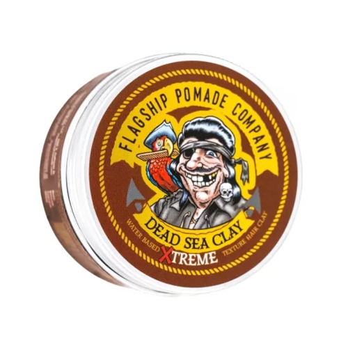 Wodna pomada do włosów Flagship Pomade Dead Sea Clay 96g w przezroczystym słoiku z brązową etykietą z piratem, papugą i żółtym napisem DEAD SEA CLAY na białym tle.