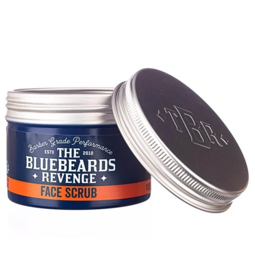 Peeling do twarzy w niebieskim opakowaniu o matowej fakturze, z metalową, błyszczącą pokrywą. Widoczny napis THE BLUEBEARDS REVENGE FACE SCRUB oraz pomarańczowy pasek z napisem 100ml. Produkt leży otwarty, a kąt ujęcia jest frontalny.