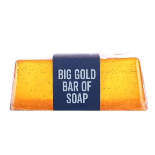 Złote mydło w kostce o prostokątnym kształcie z zaokrąglonymi krawędziami, na białym tle. Granatowa etykieta z napisem BIG GOLD BAR OF SOAP i niewielkie bąbelki na powierzchni.