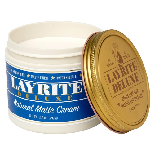 Biały, matowy pojemnik z pomadą Layrite Natural Matte Cream 297g, z niebieskim napisem i złotym wieczkiem. Ukośny widok, wieczko odsunięte, wnętrze widoczne, na jasnym, neutralnym tle.