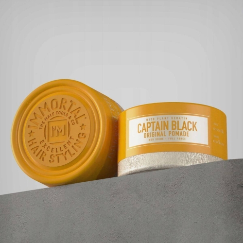 Immortal pomada do włosów Captain Black 150 ml w żółtym opakowaniu, z napisem „CAPTAIN BLACK ORIGINAL POMADE”. Pojemnik ma matową górę i metaliczne dno, ustawiony lekko ukośnie na szarym tle, podkreślając unikalny design.