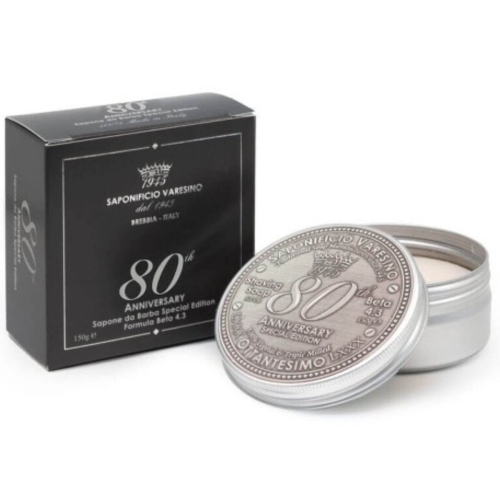 Saponificio Varesino 80th Anniversary mydło do golenia w metalowym okrągłym opakowaniu 150 g, z napisem na wieczku. Na białym tle, z czarnym eleganckim kartonowym pudełkiem w tle, o gładkiej, matowej teksturze.