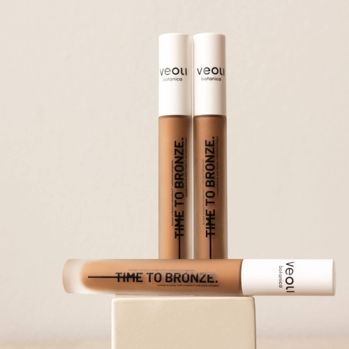 Kremowy bronzer TIME TO BRONZE w brązowym odcieniu, 30 ml z białą zakrętką i czarnym nadrukiem, na jasnym tle. Obok dwa bronzery o różnych odcieniach, z gładką, błyszczącą powierzchnią.