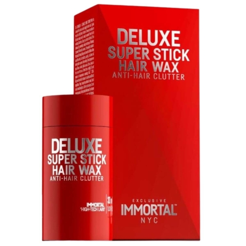 Czerwony sztyft do włosów 30 ml z napisem DELUXE SUPER STICK HAIR WAX i ANTI-HAIR CLUTTER, matowe opakowanie, stoi na krawędzi. W tle białe pudełko z logo IMMORTAL i napisem EXCLUSIVE NYC.