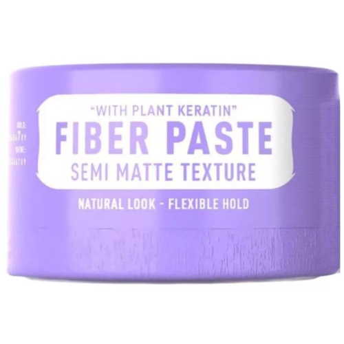 Matowy krem do stylizacji włosów w fioletowym, okrągłym opakowaniu z napisami FIBER PASTE i SEMI MATTE TEXTURE. Zapewnia naturalny wygląd i elastyczne utrwalenie. Produkt stoi na jednolitym tle, bez dodatków.