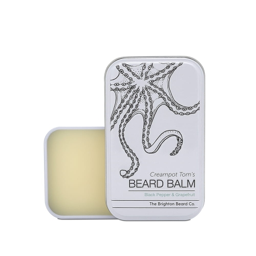 Balsam do brody w metalowej puszce z ośmiornicą na pokrywie. Jasny kolor, napis Creampot Tom's BEARD BALM, zapach Black Pepper & Grapefruit. Puszka otwarta, wielkość dłoni, na białym tle.