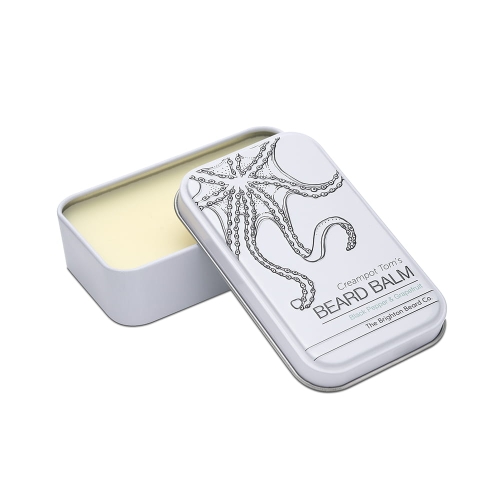 Biały metalowy pojemnik z otwartą pokrywką, zawierający jasny balsam do brody. Na froncie czarny rysunek ośmiornicy i napis Creampot Tom's BEARD BALM oraz zapach Black Pepper & Grapefruit.