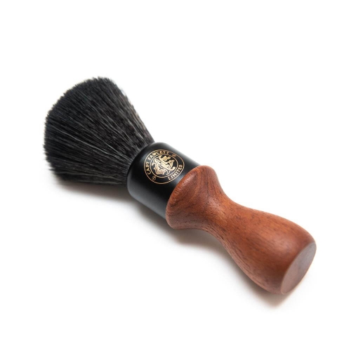 Bristle shaving brush with a wooden handle, featuring a black ferrule adorned with a logo. The brush is shown at a 45-degree angle, highlighting its rounded shape and soft bristles against a white background.