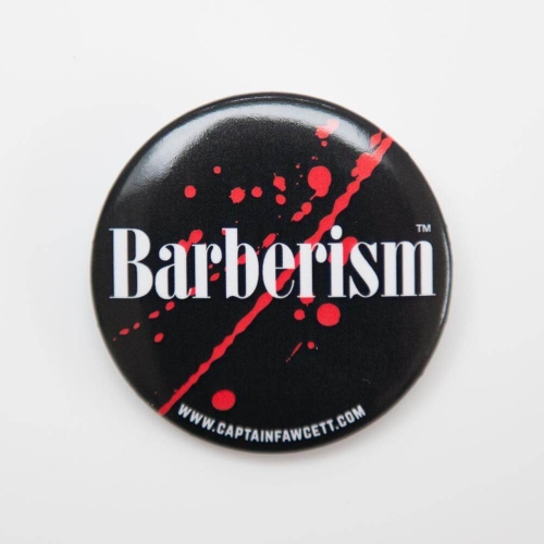 Czarny okrągły przycisk z białym napisem Barberism i czerwonymi plamami, widok frontalny.