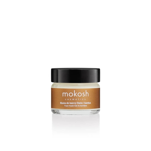 Biała maska do twarzy w szklanym słoiku z ciemną pokrywką i etykietą mokosh cosmetics, Owies i bambus na białym tle.