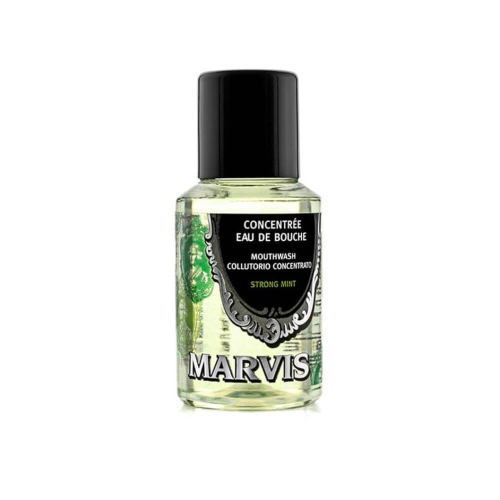 Pojemnik płynu do płukania jamy ustnej Marvis z zielonym płynem, ciemną zakrętką i przezroczystym dnem. Na etykiecie napisy CONCENTRÉE EAU DE BOUCHE i MOUTHWASH COLUTTORIO CONCENTRATO STRONG MINT z czarno-zielonym wzorem.